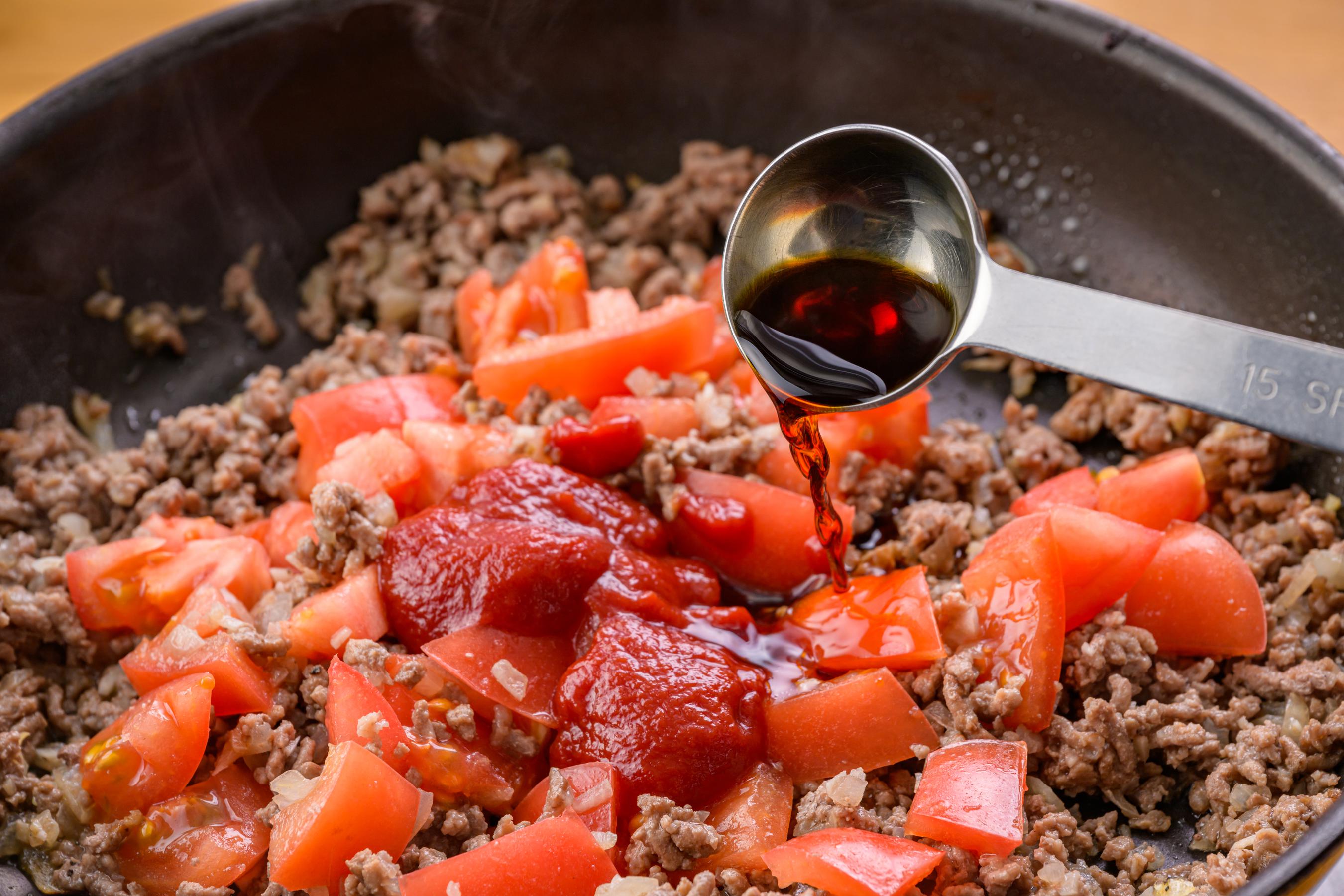Adding tomatoes and seasonings to ground beef