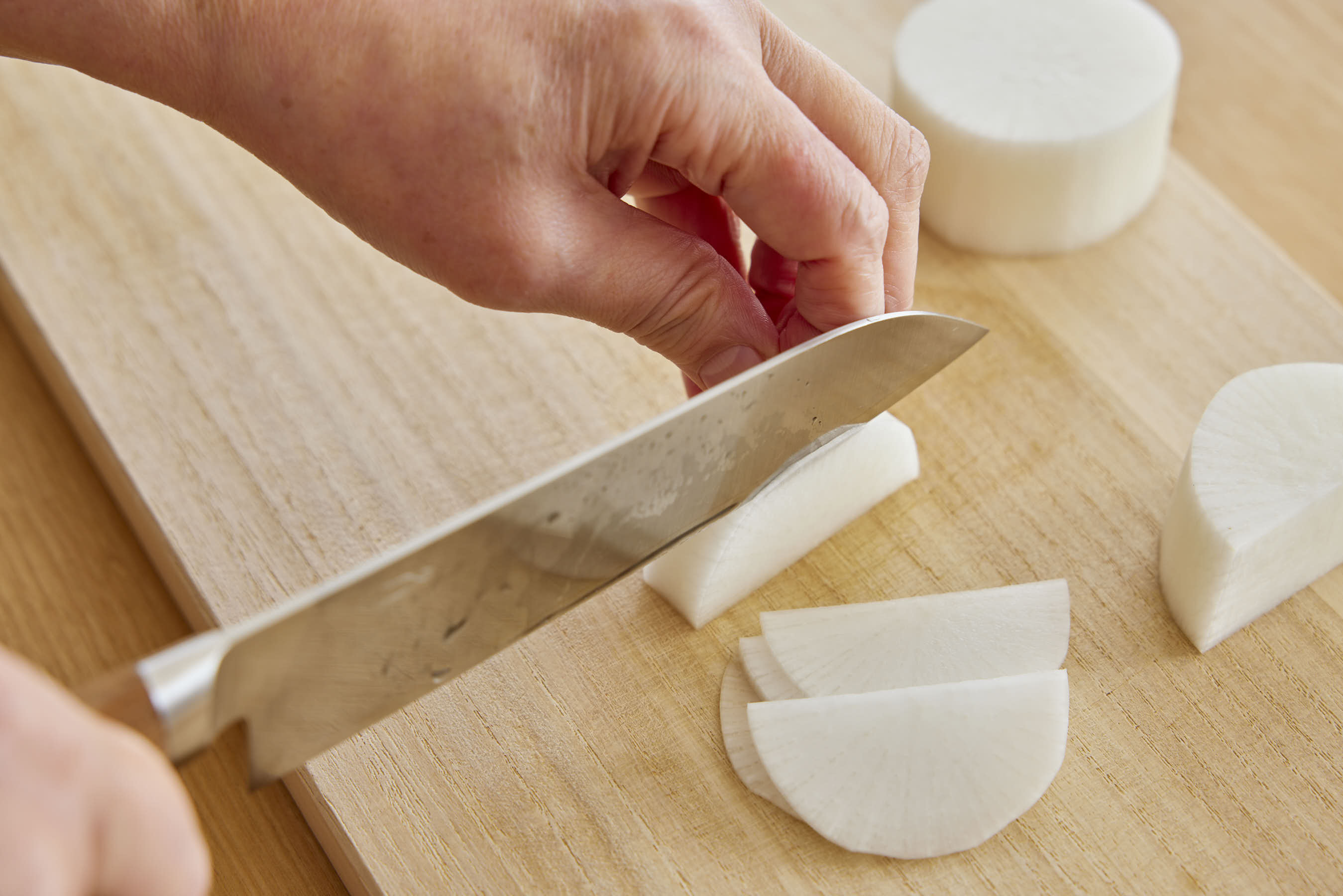 Slicing daikon radish on a cutting board