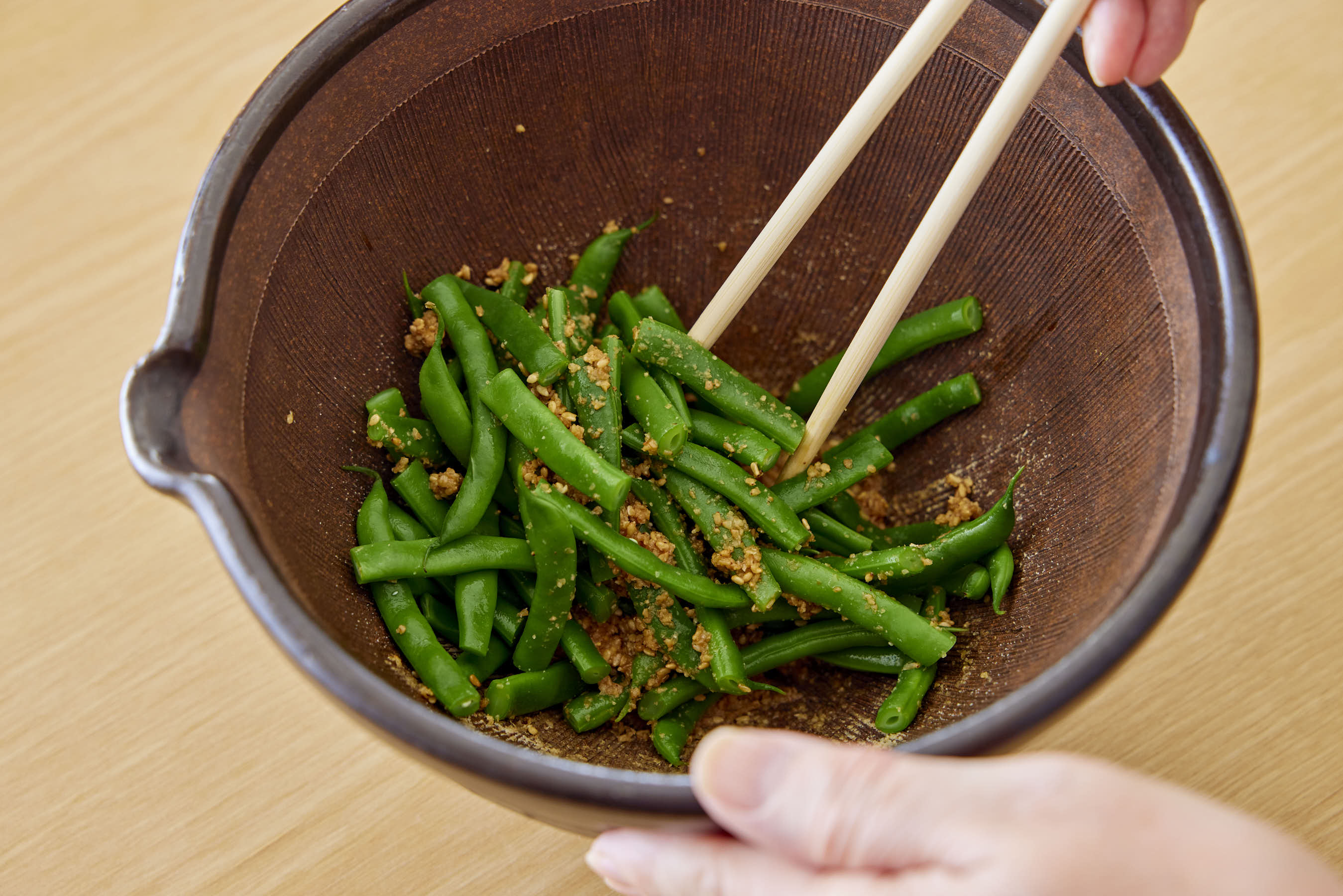 Mixing the green beans with the sesame dressing
