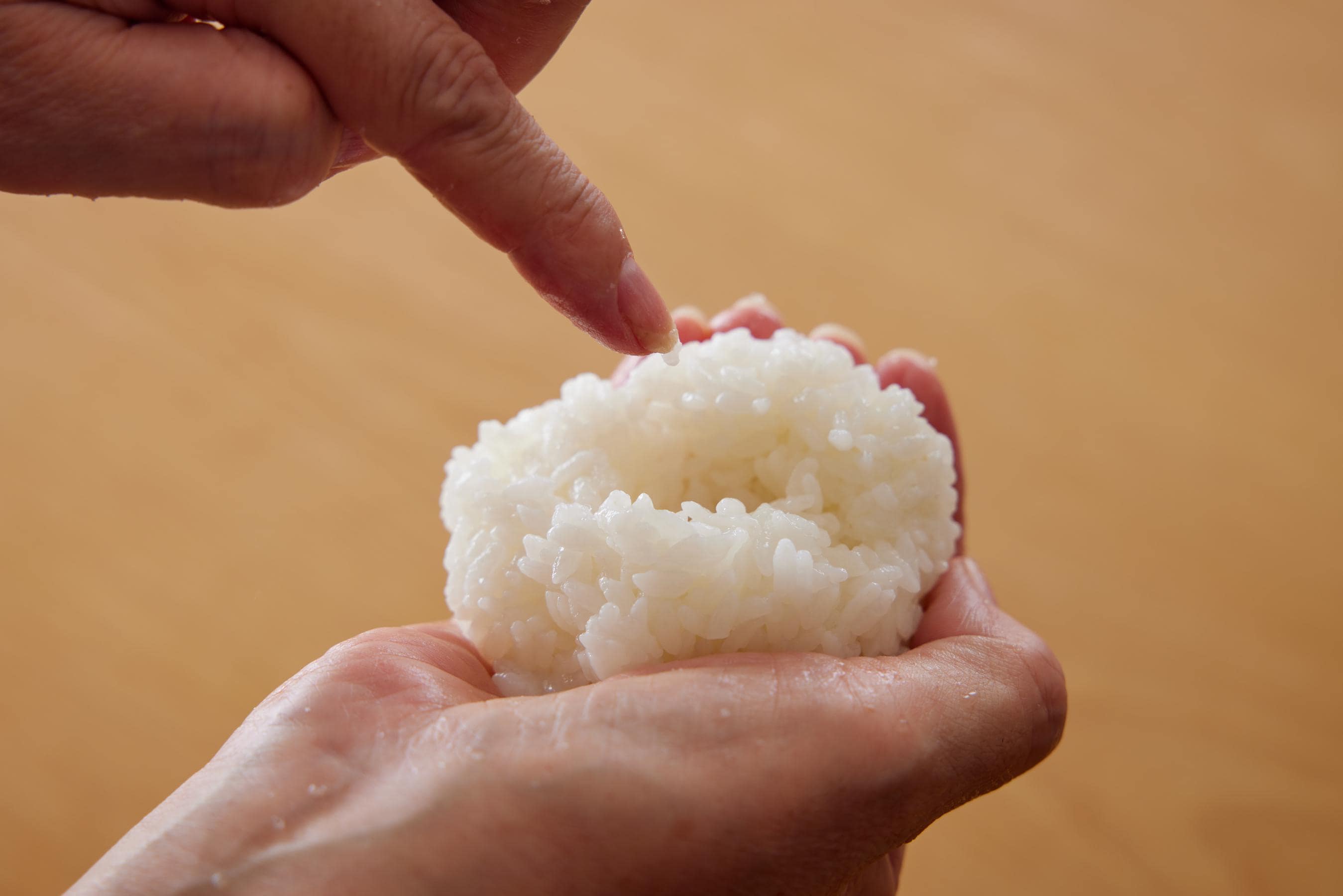 forming a small hole in the center of the rice ball