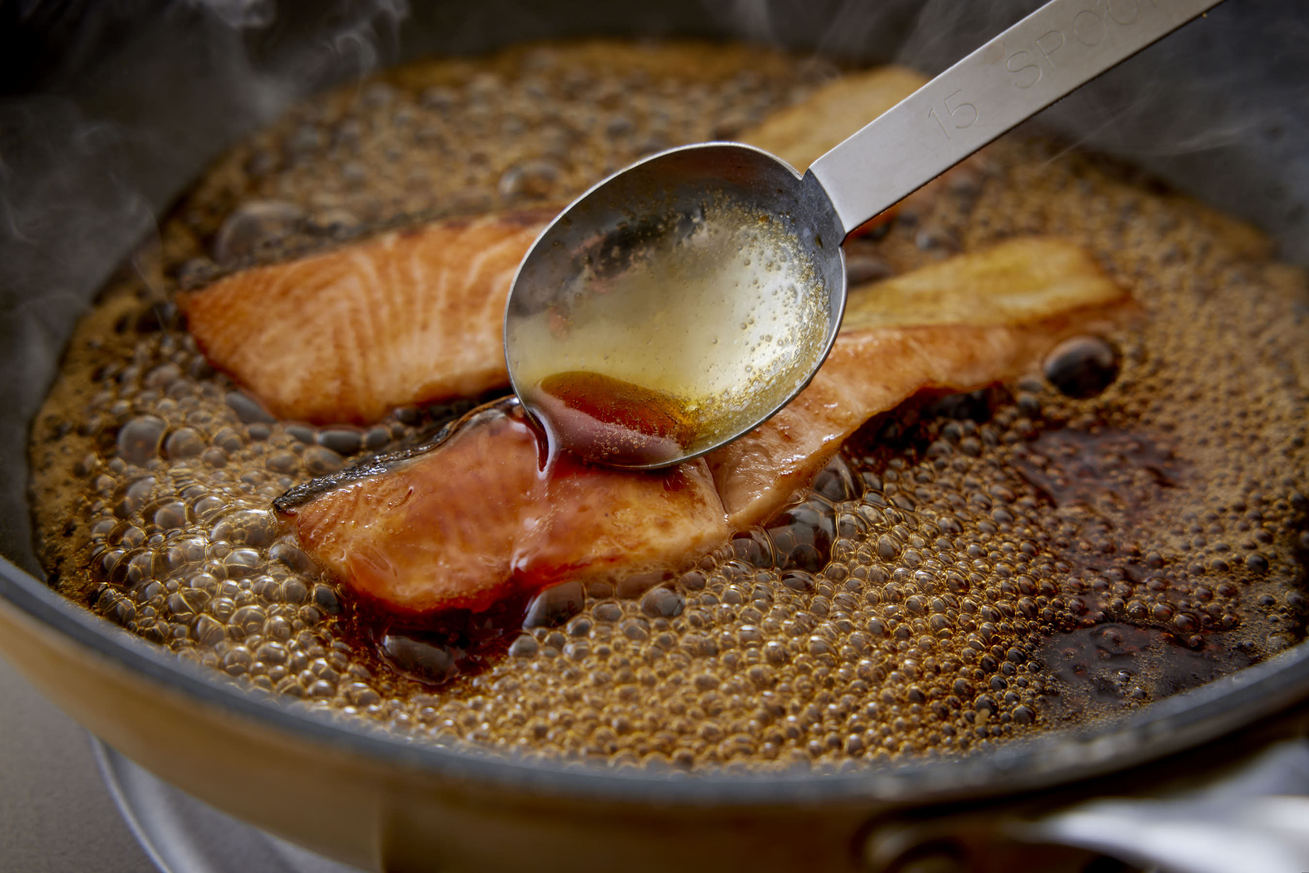 Spooning the Teriyaki sauce over the salmon