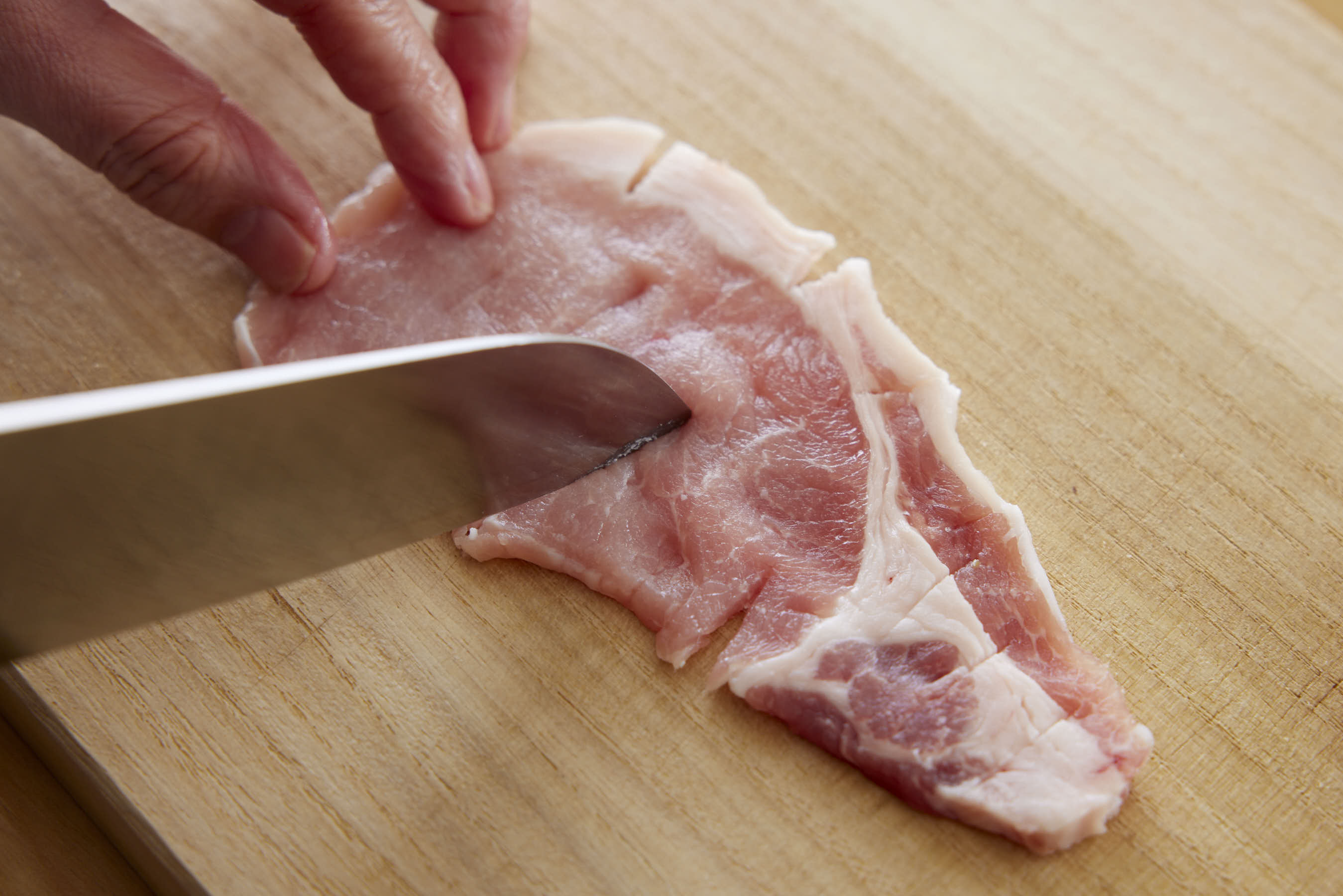 Cutting slits into the surface of the meat with the tip of a knife