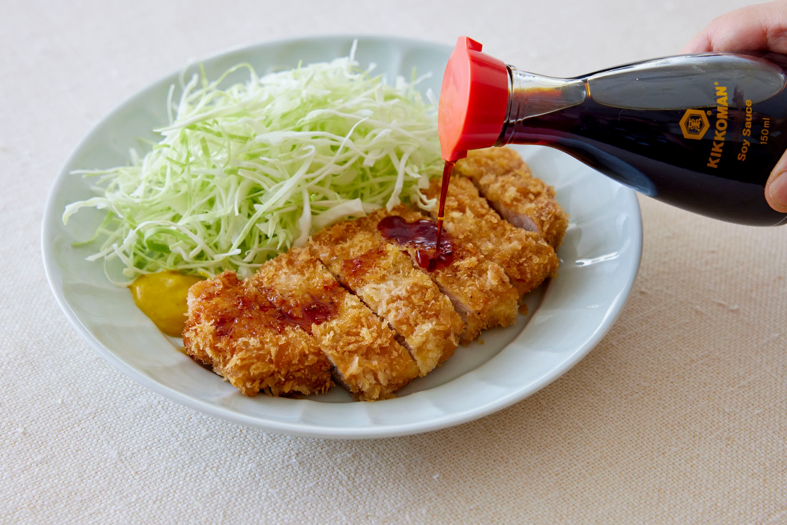 Pouring Kikoman Soy Sauce over Tonkatsu