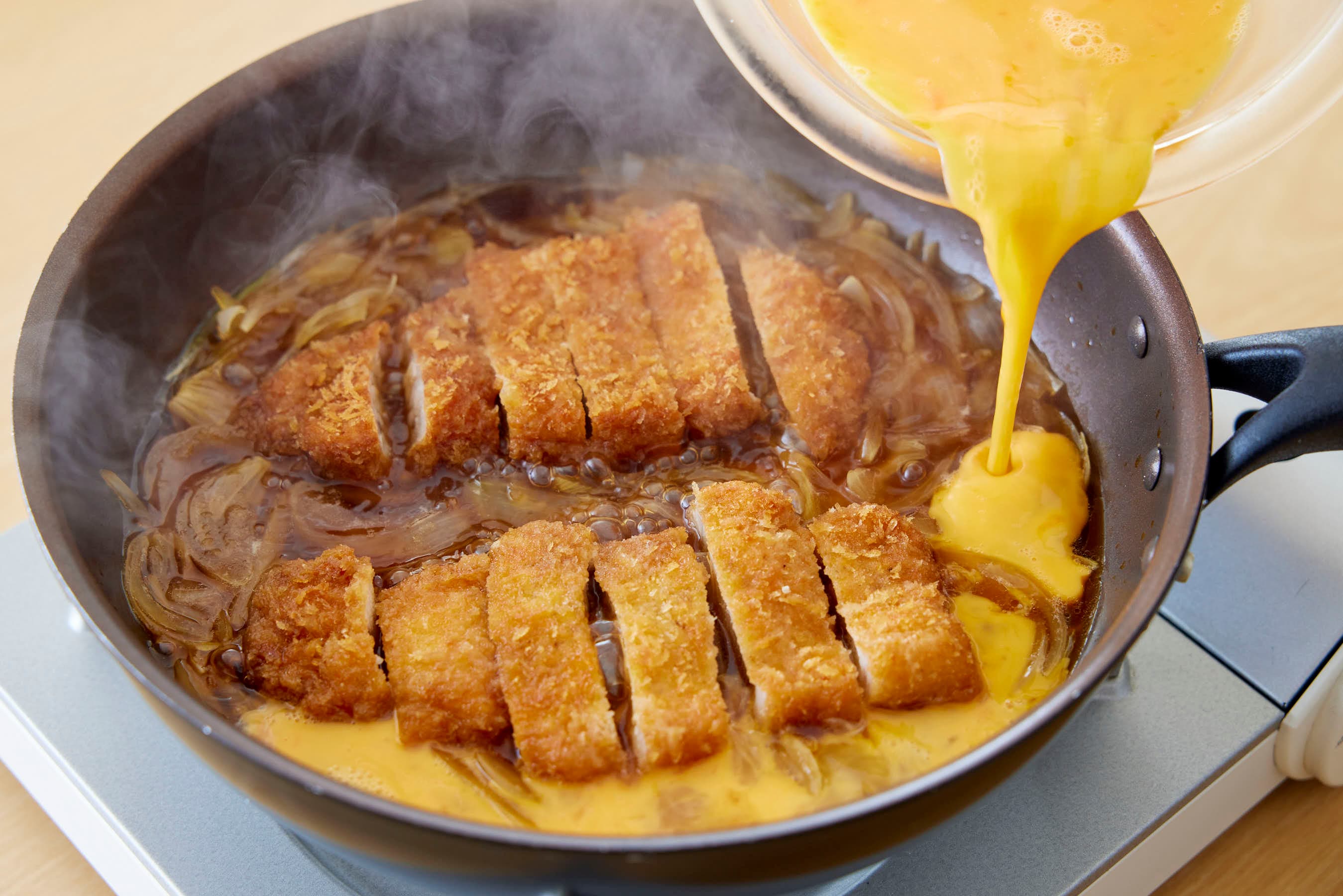 Pouring the beaten eggs over the pan