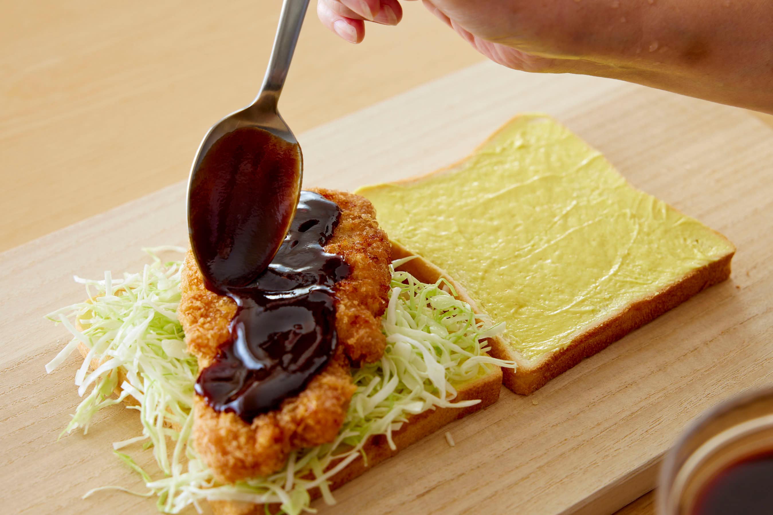 Drizzling Tonkatsu sauce over the Tonkatsu