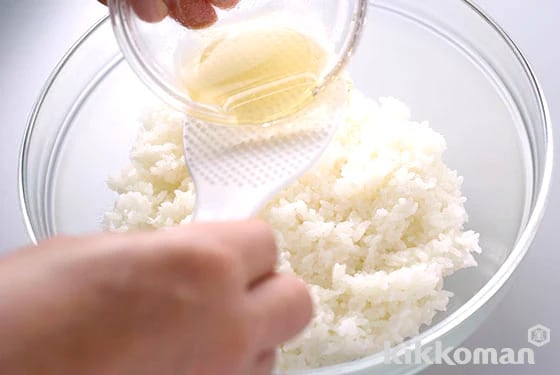 4. Prepare the vinegar mixture. Place the cooked rice into a bowl, pour the vinegar mixture over the rice and let sit for 1 minute.