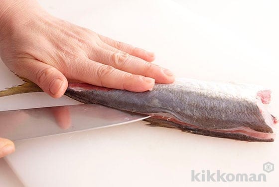 Place the 2-layer filleted horse mackerel with the bones facing downwards, insert the knife from the flank until it reaches the backbone, slide the knife towards the tail to make an incision.