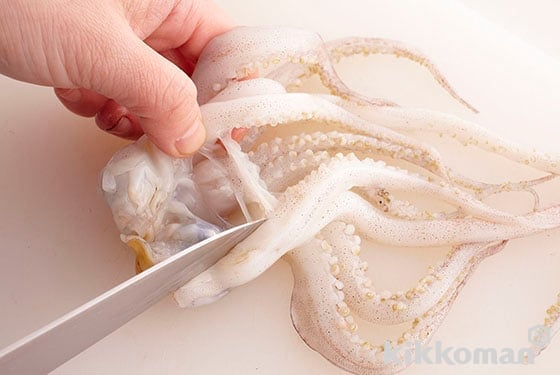 Place your knife blade just below the eyes and cut away the tentacles and innards. Place your knife into the cylindrical part and spread the tentacles, remove the hard beak and eyes. Scrape off small suction cups with your knife blade and cut away large ones.