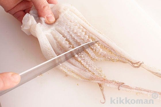 Place your knife blade just below the eyes and cut away the tentacles and innards. Place your knife into the cylindrical part and spread the tentacles, remove the hard beak and eyes. Scrape off small suction cups with your knife blade and cut away large ones.